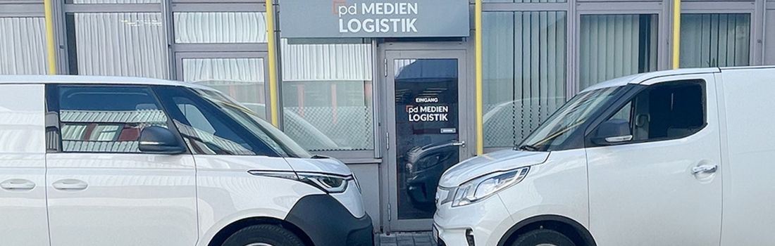 Zwei Elektrotransporter – VW ID. Buzz Cargo und Maxus – vor dem Firmengebäude der pd.M, bereit für emissionsfreie Zustellung.“