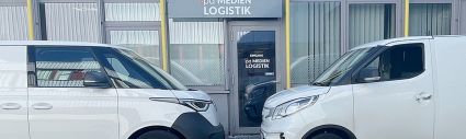 Zwei Elektrotransporter – VW ID. Buzz Cargo und Maxus – vor dem Firmengebäude der pd.M, bereit für emissionsfreie Zustellung.“
